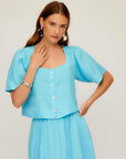 Woman wearing light blue Pia Poof Sleeve Linen Top with square neck, short puff sleeves, and button front closure.
