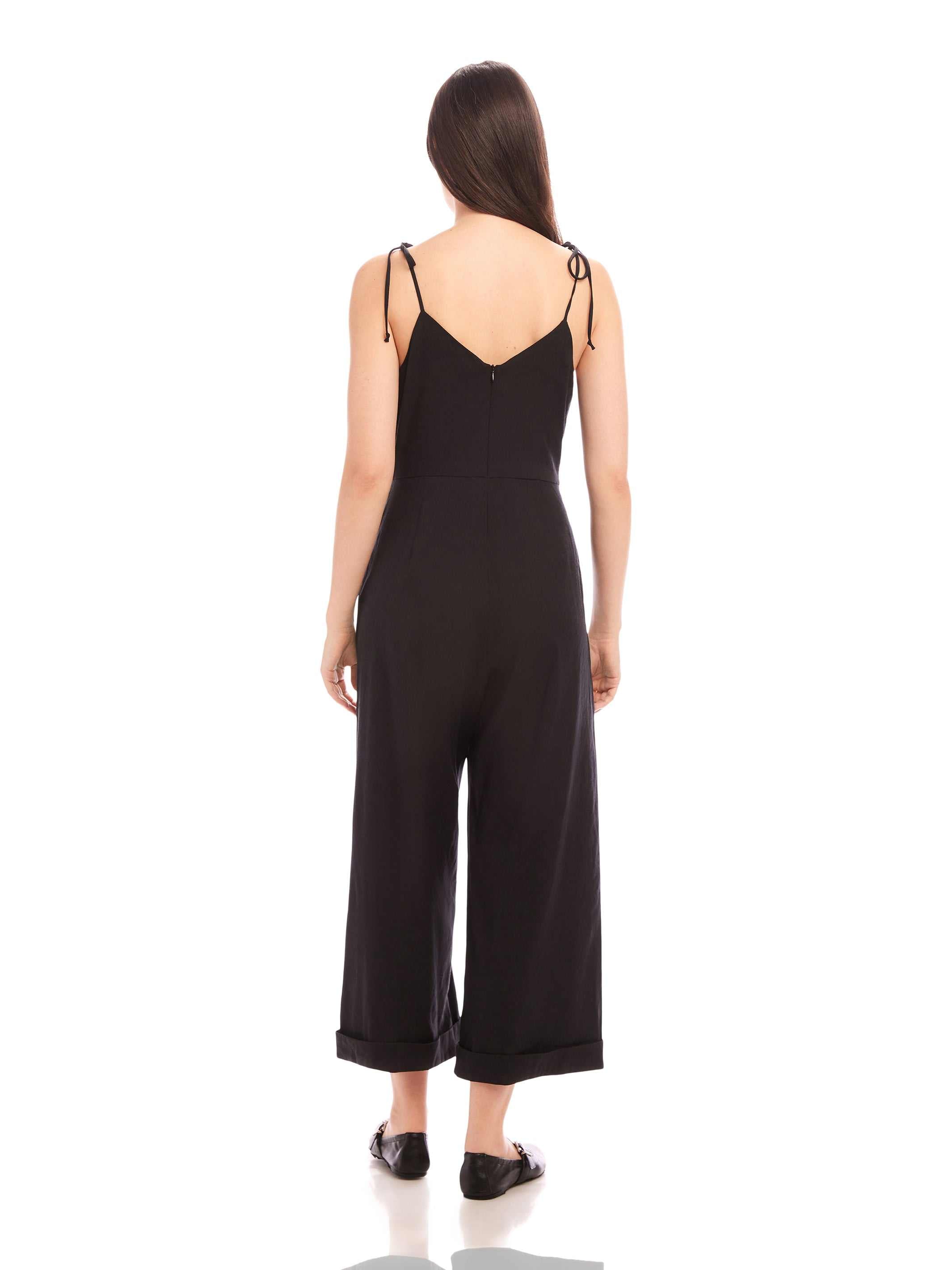 Back view of woman wearing black Dana Cropped Jumpsuit with adjustable tie straps and cuffed wide legs