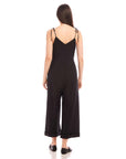 Back view of woman wearing black Dana Cropped Jumpsuit with adjustable tie straps and cuffed wide legs