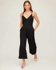 Woman wearing a black Dana Cropped Jumpsuit with wide cropped legs, adjustable tie straps, and side pockets.