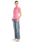 Woman wearing pink Emmeline blouse made of silky cupro material with mock cowl neck and split cap sleeves paired with blue jeans and silver heels