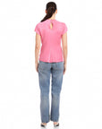Back view of woman wearing pink Emmeline blouse made from silky cupro material with split cap sleeves and keyhole closure paired with blue jeans