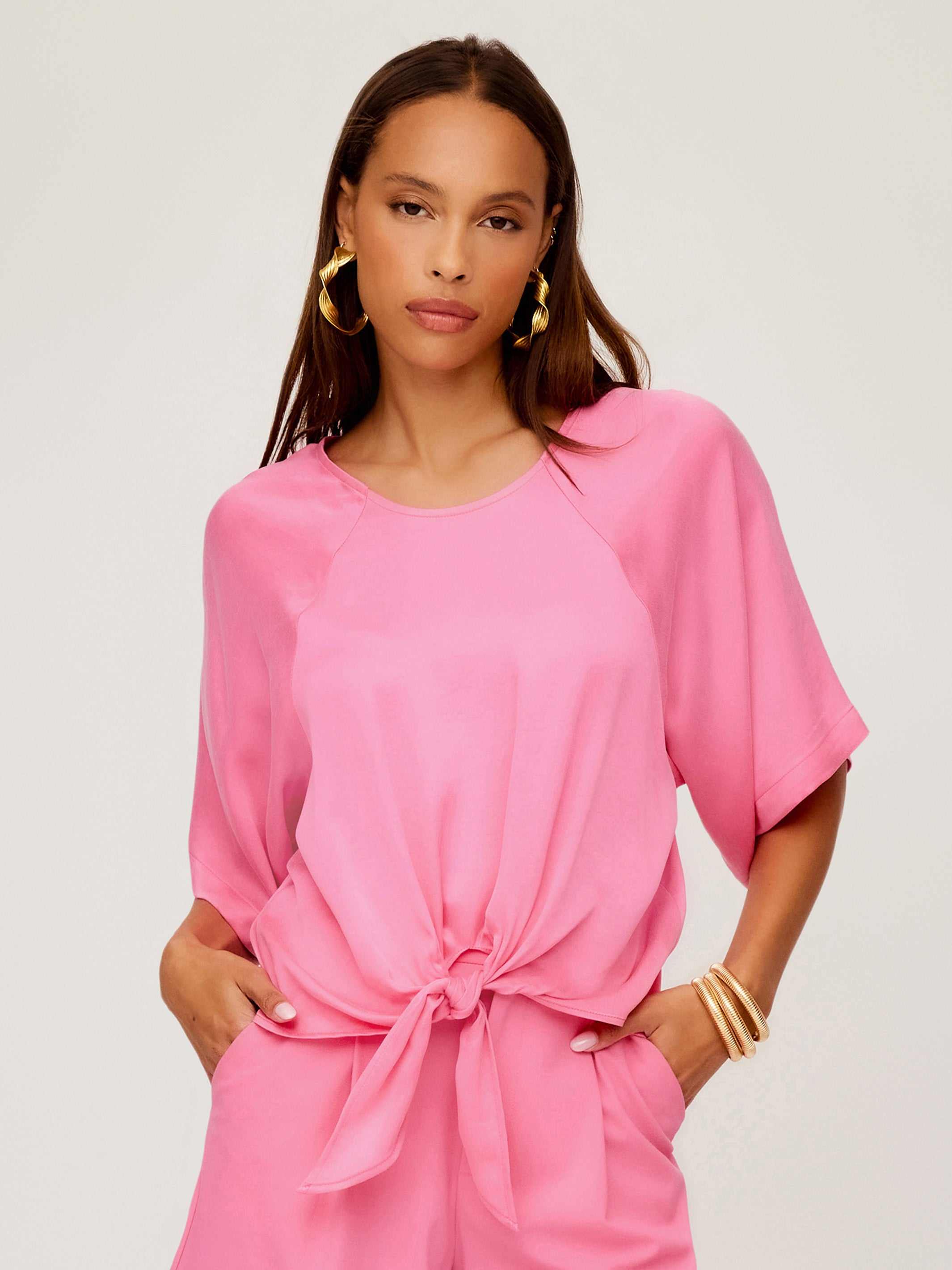 Woman wearing a pink Seline Tie-Front Top with dolman sleeves and a boatneck design, styled with matching pants.