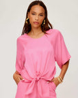 Woman wearing a pink Seline Tie-Front Top with dolman sleeves and a boatneck design, styled with matching pants.