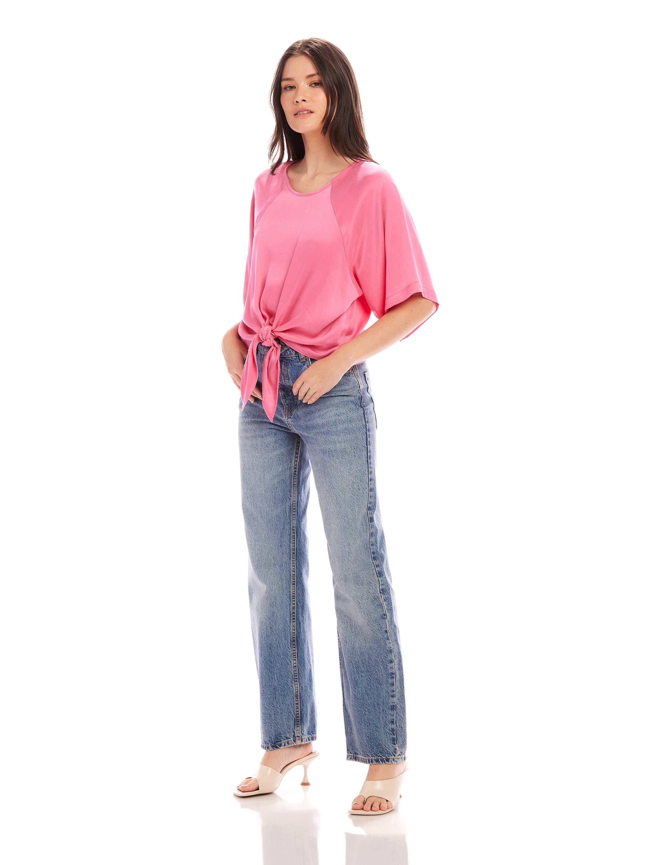 Woman wearing pink Seline Tie-Front Top with dolman sleeves and blue high waist jeans