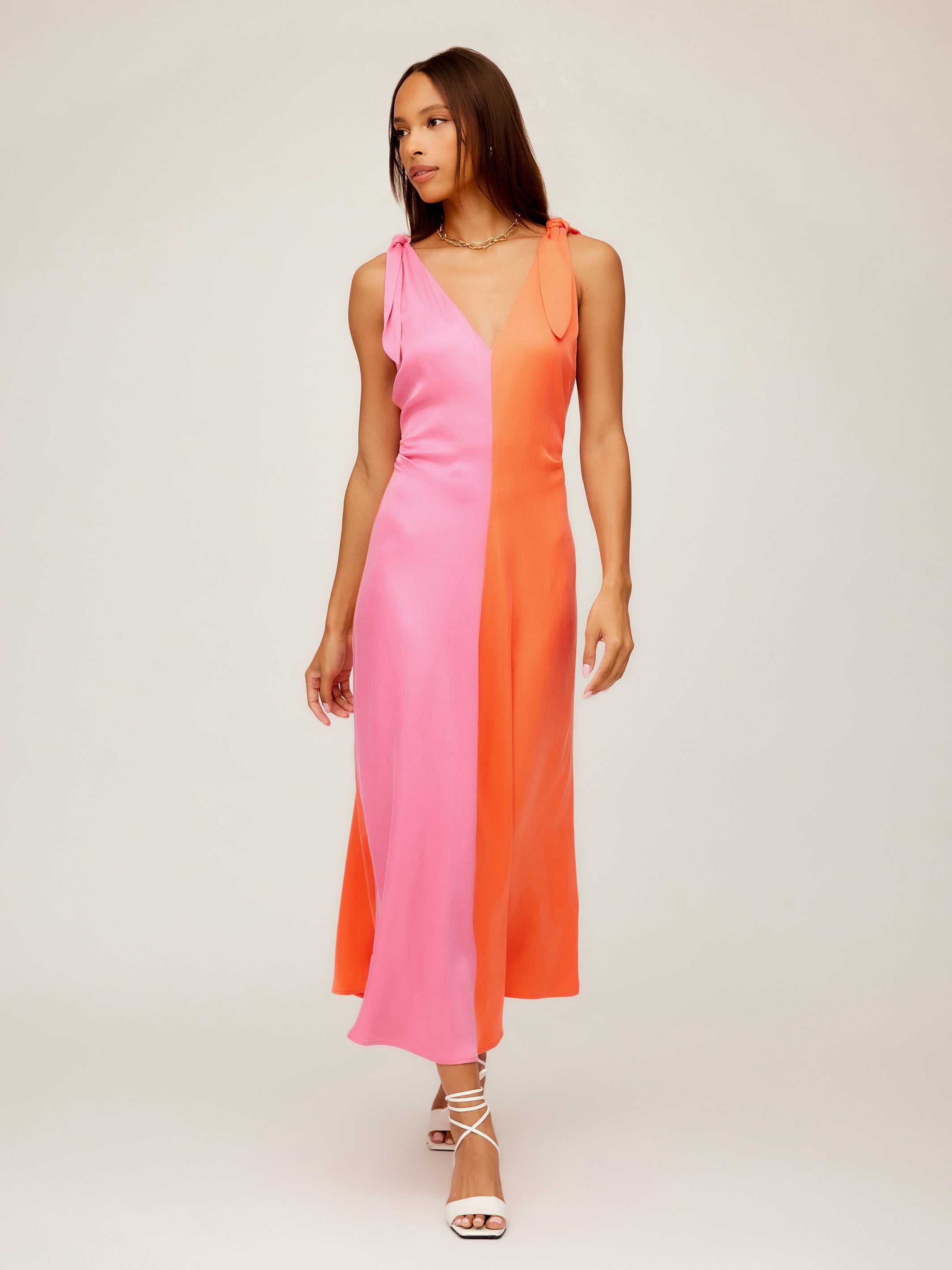Woman wearing Verity Two-Tone Midi Dress in coral and pink with A-line silhouette and pleated detail
