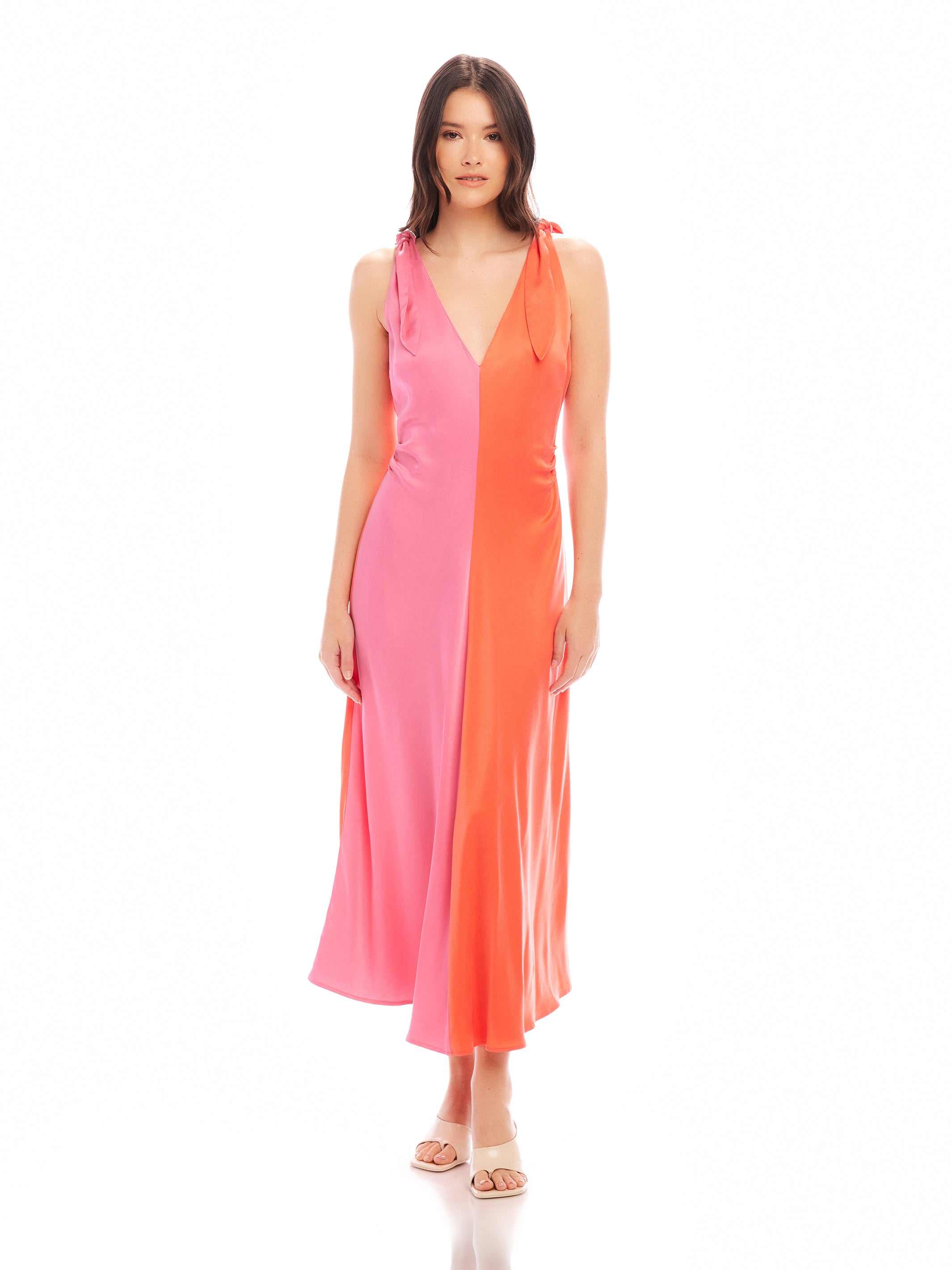 Woman wearing Verity Two-Tone Midi Dress in coral and pink with pleated A-line silhouette and low V-neck