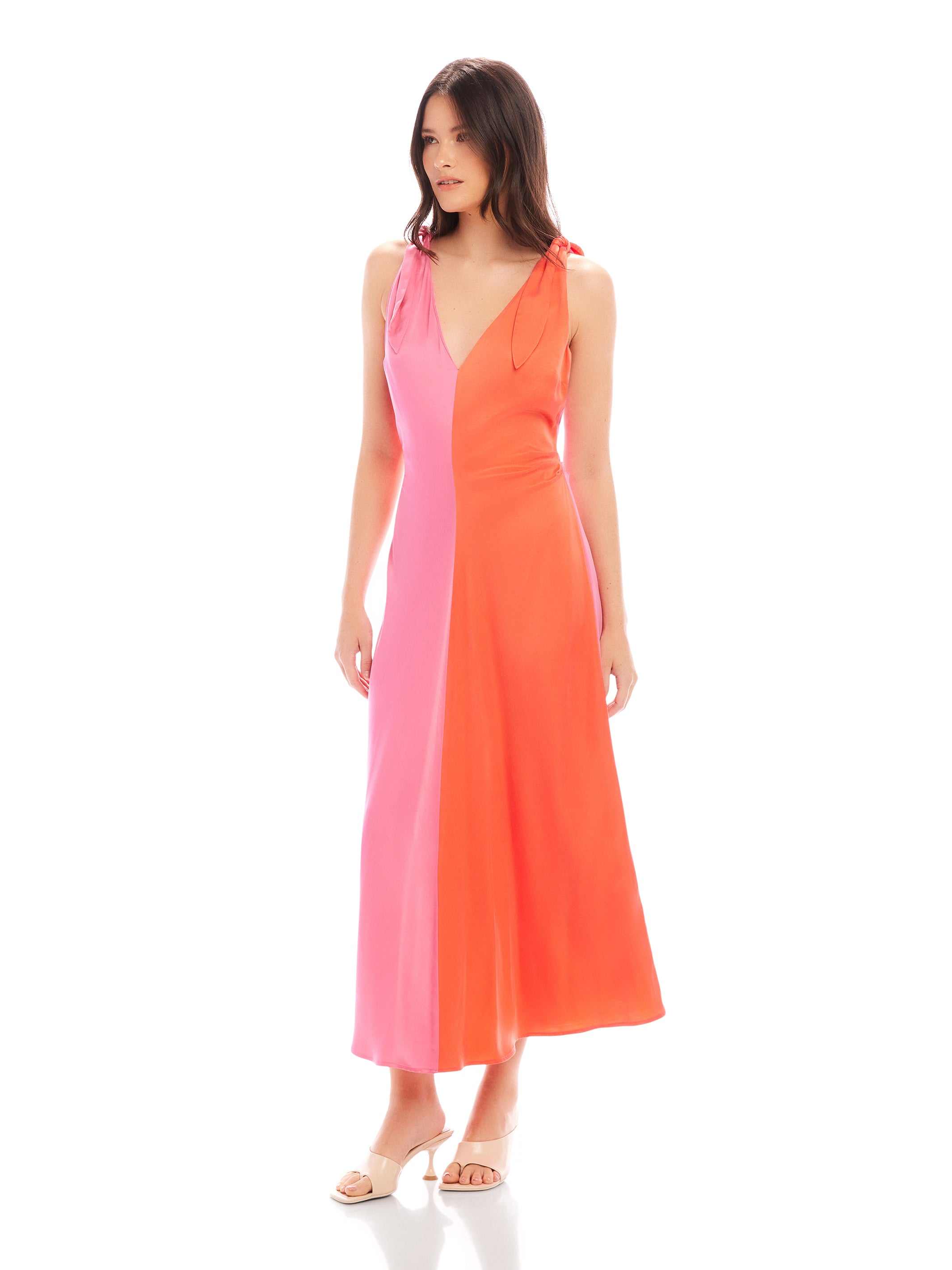 Verity Two-Tone Midi Dress with coral and pink color blocking, pleated A-line silhouette, low V-neck, and midi length.