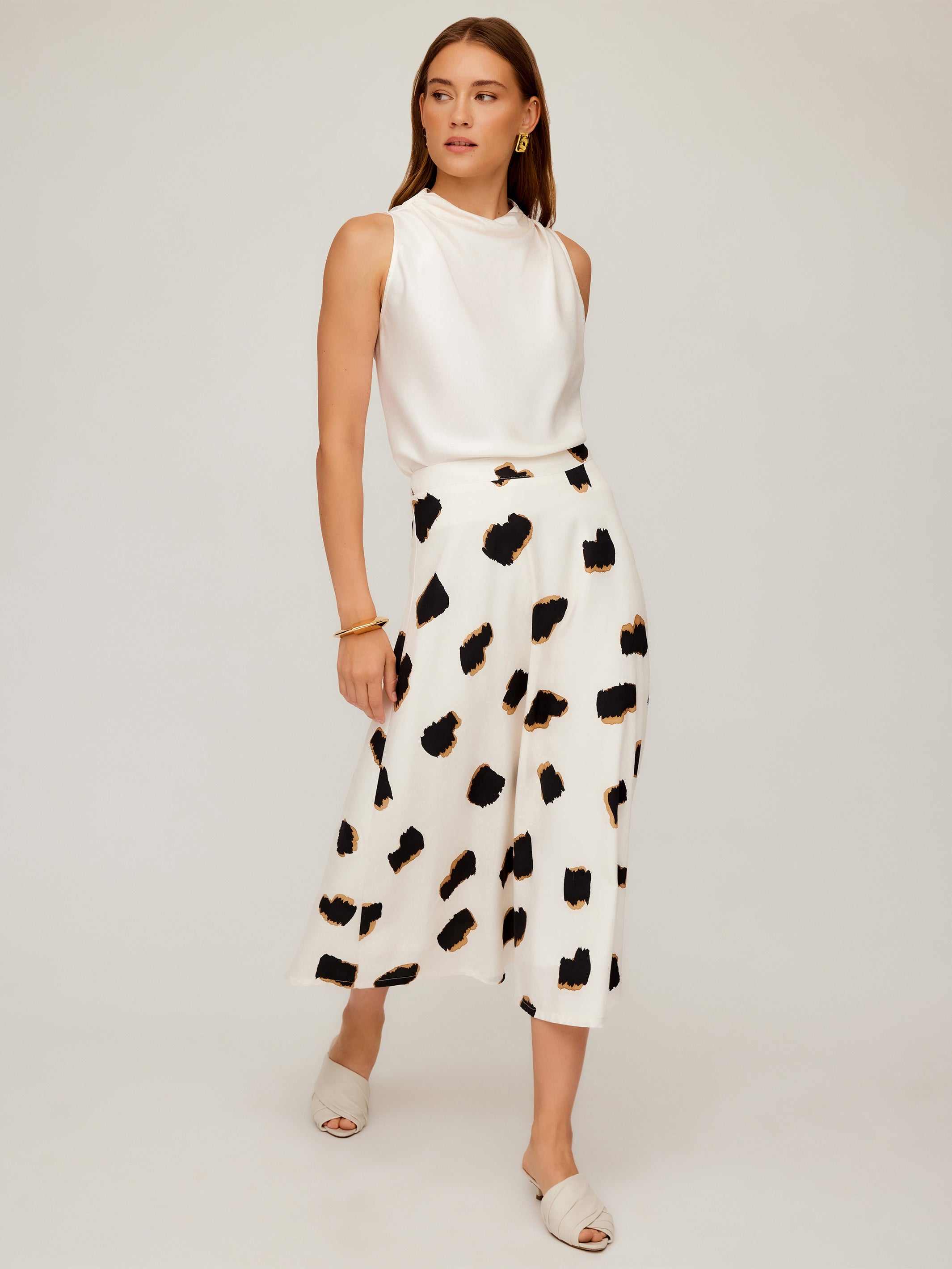 Woman wearing a high-waisted midi Lexi Skirt with Sahara Twill print and sleeveless white top
