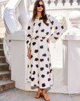 Woman wearing a high-waisted, flowy Lexi Skirt midi in white Sahara Twill print with black and tan spots, paired with a matching top and sandals.