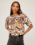 Nadine Bow Detail Top with brown and white stamped batik print, short puff sleeves, front tie closure, and semi-cropped boxy fit modeled with high waist jeans