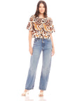 Woman wearing Nadine Bow Detail Top with front tie and short puff sleeves paired with high waist jeans