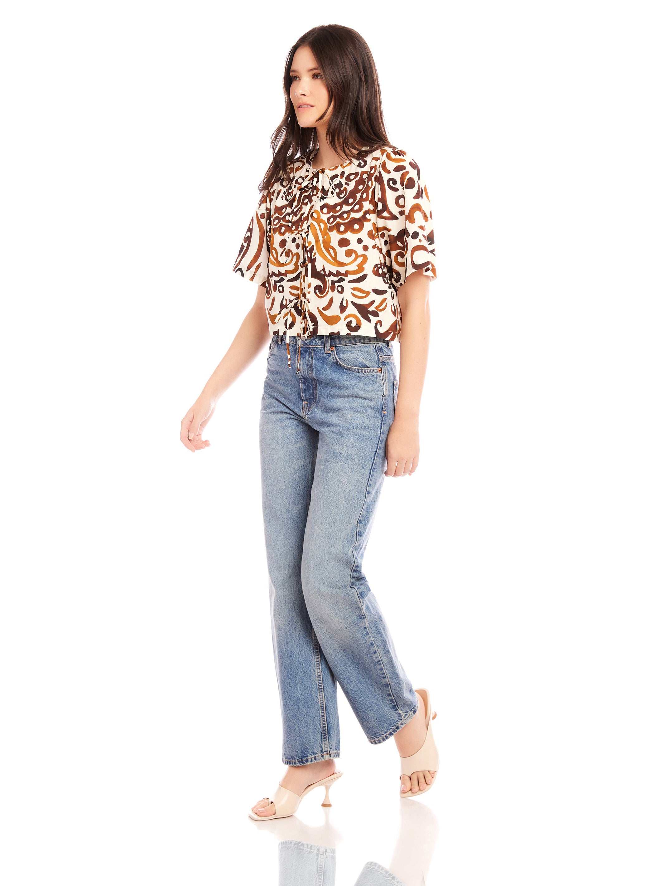 Woman wearing Nadine Bow Detail Top with front tie closure and high-waisted jeans