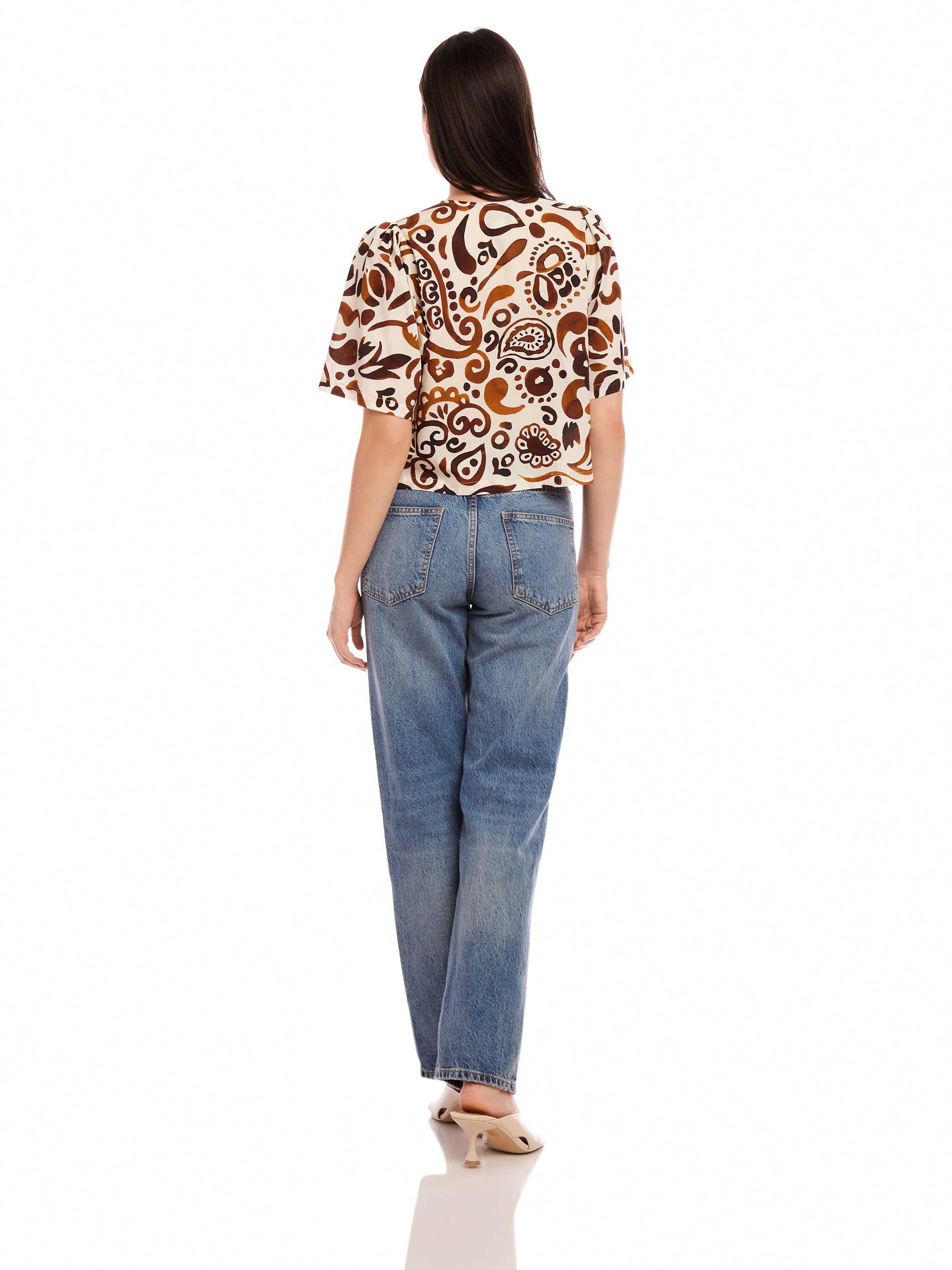 Woman wearing Nadine Bow Detail Top with stamped batik cotton poplin and high waist jeans, back view
