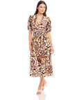Woman wearing a Poppy Shirred Waist Dress with brown and white paisley print, V-neckline, short puff sleeves, elasticized waist, and side slit.