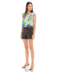 Woman wearing sleeveless Sami top with botanical scarf print and adjustable waist tie paired with black high waist shorts