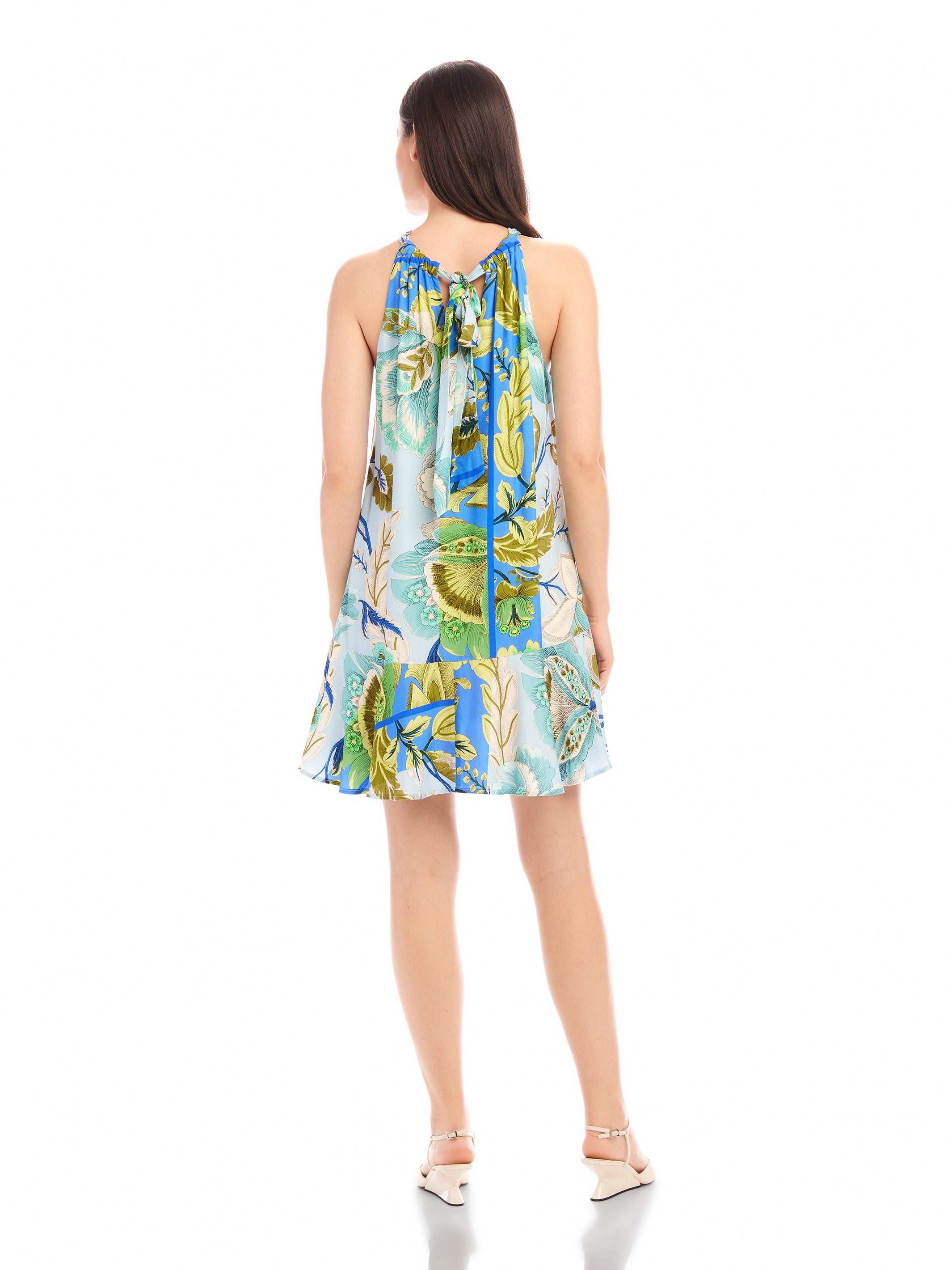 Back view of a woman wearing a sleeveless Brenda Ruffle Hem Dress with botanical floral scarf print and ruffle hem.