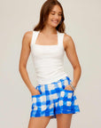 Woman wearing Betty Picnic Shorts with blue and white watercolor check print and white sleeveless top smiling