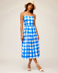 Woman wearing blue and white Costa Dress with adjustable spaghetti straps and square neck, styled with a beige hat and white sandals