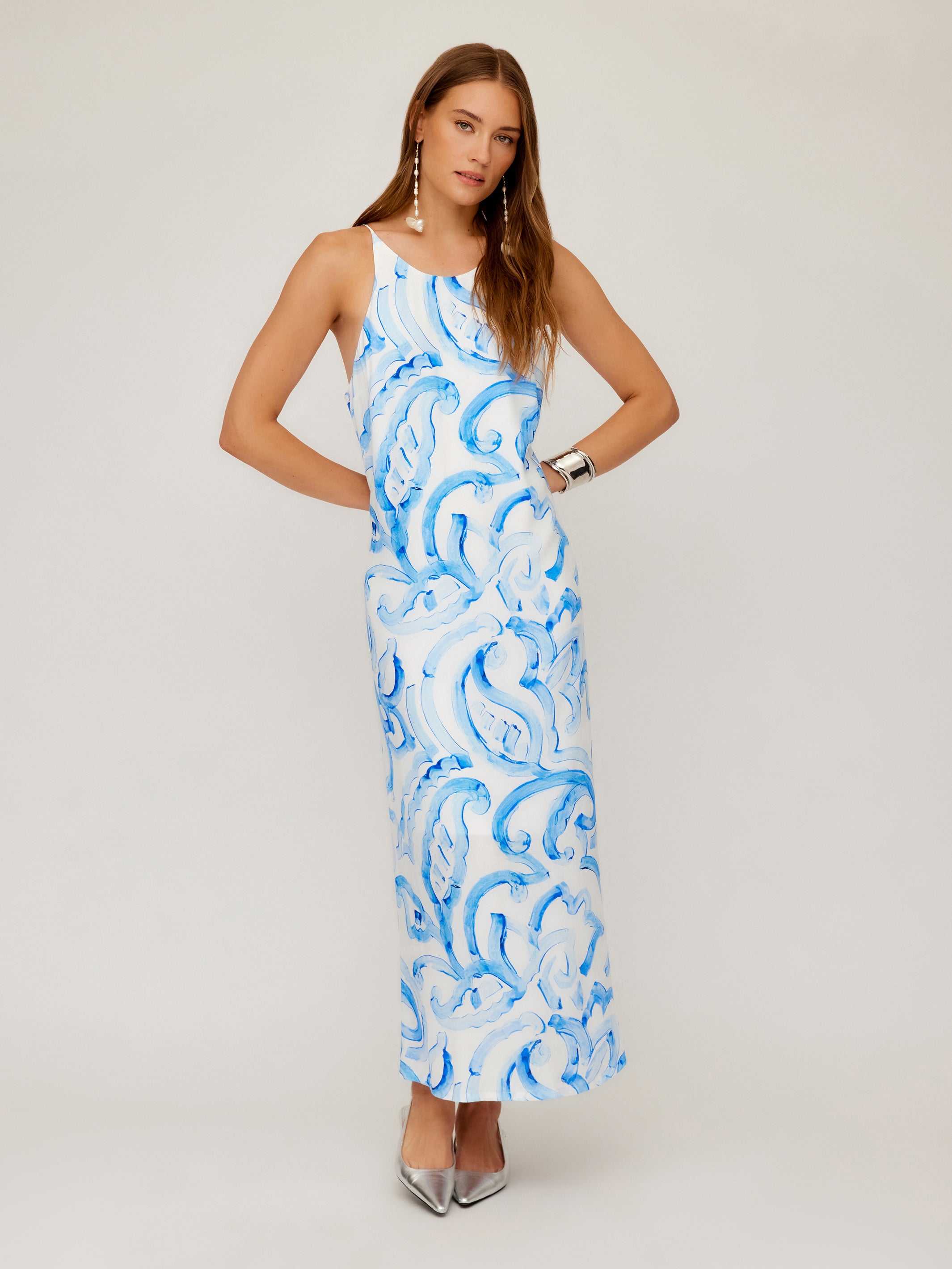 Woman wearing Sera A-Line Dress in blue painted paisley print with adjustable spaghetti straps and maxi length