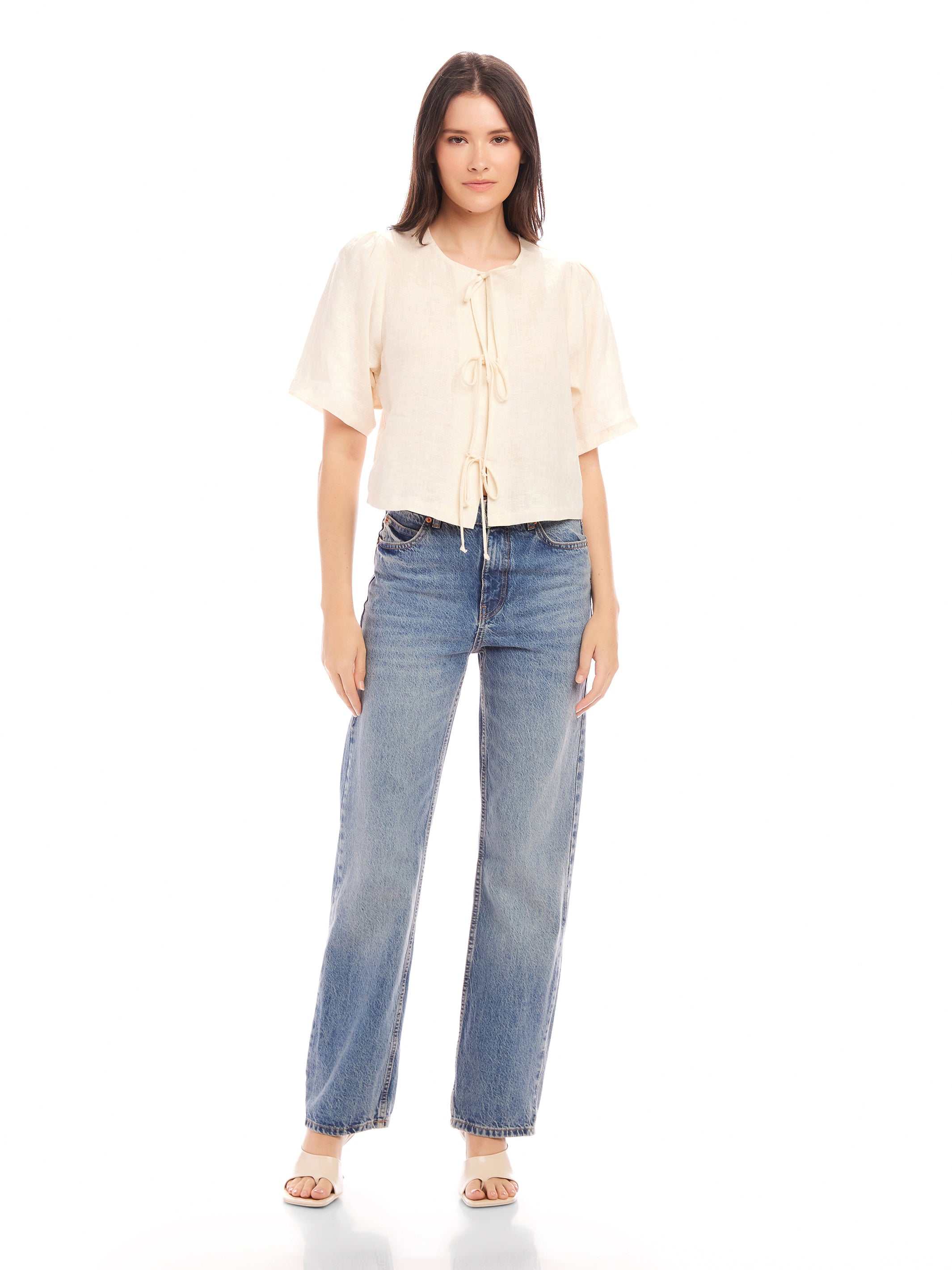 Nadine Bow Detail top in cream linen with front tie closure and short puff sleeves paired with high waist blue jeans