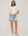 Woman wearing Nadine Bow Detail Top with front tie closure and short puff sleeves paired with distressed high waist denim shorts