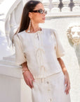 Woman wearing Nadine Bow Detail semi cropped linen top with front tie closures and short puff sleeves