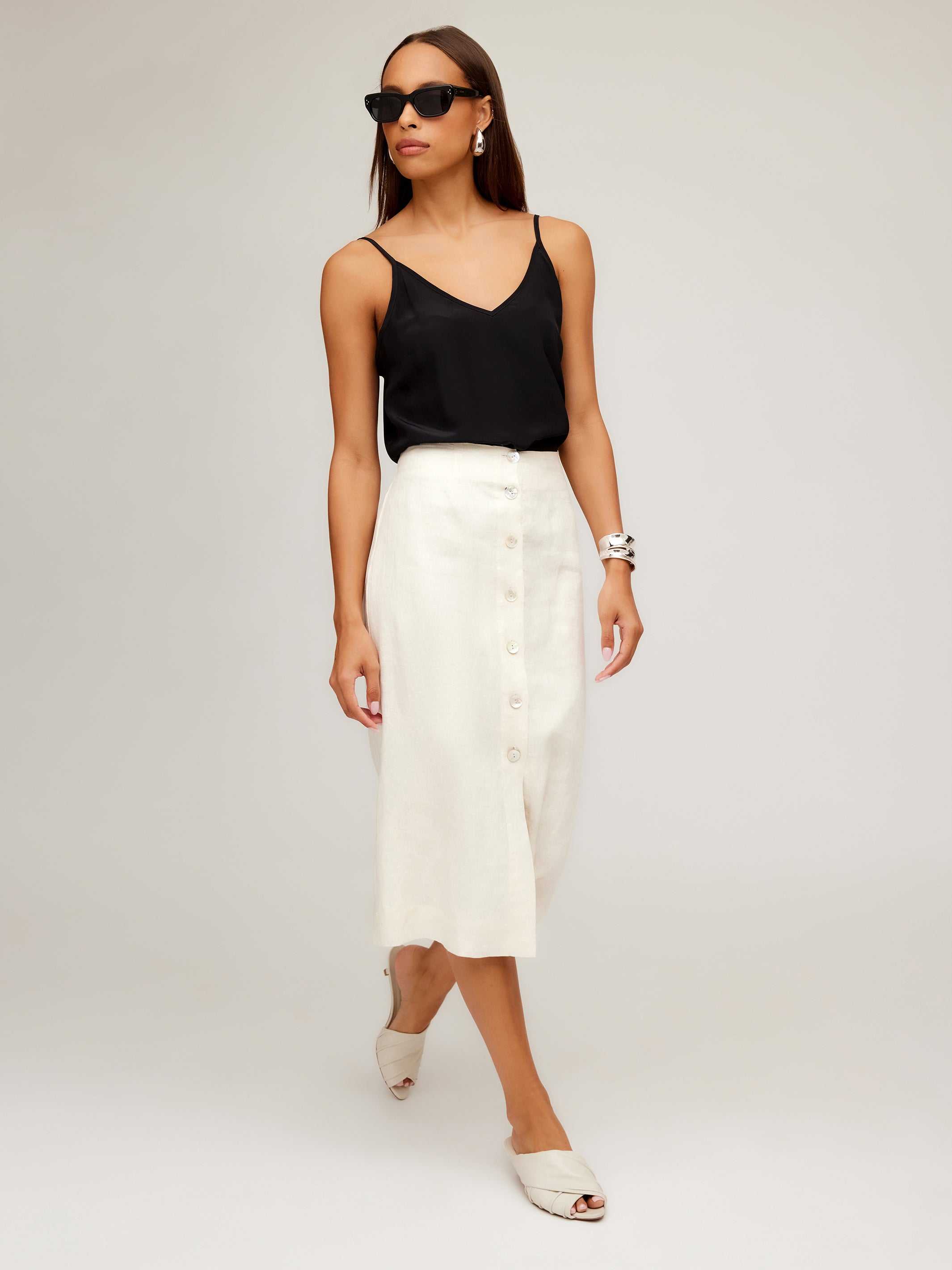 Woman wearing a white Lori Midi Skirt with front buttons and a black sleeveless top.