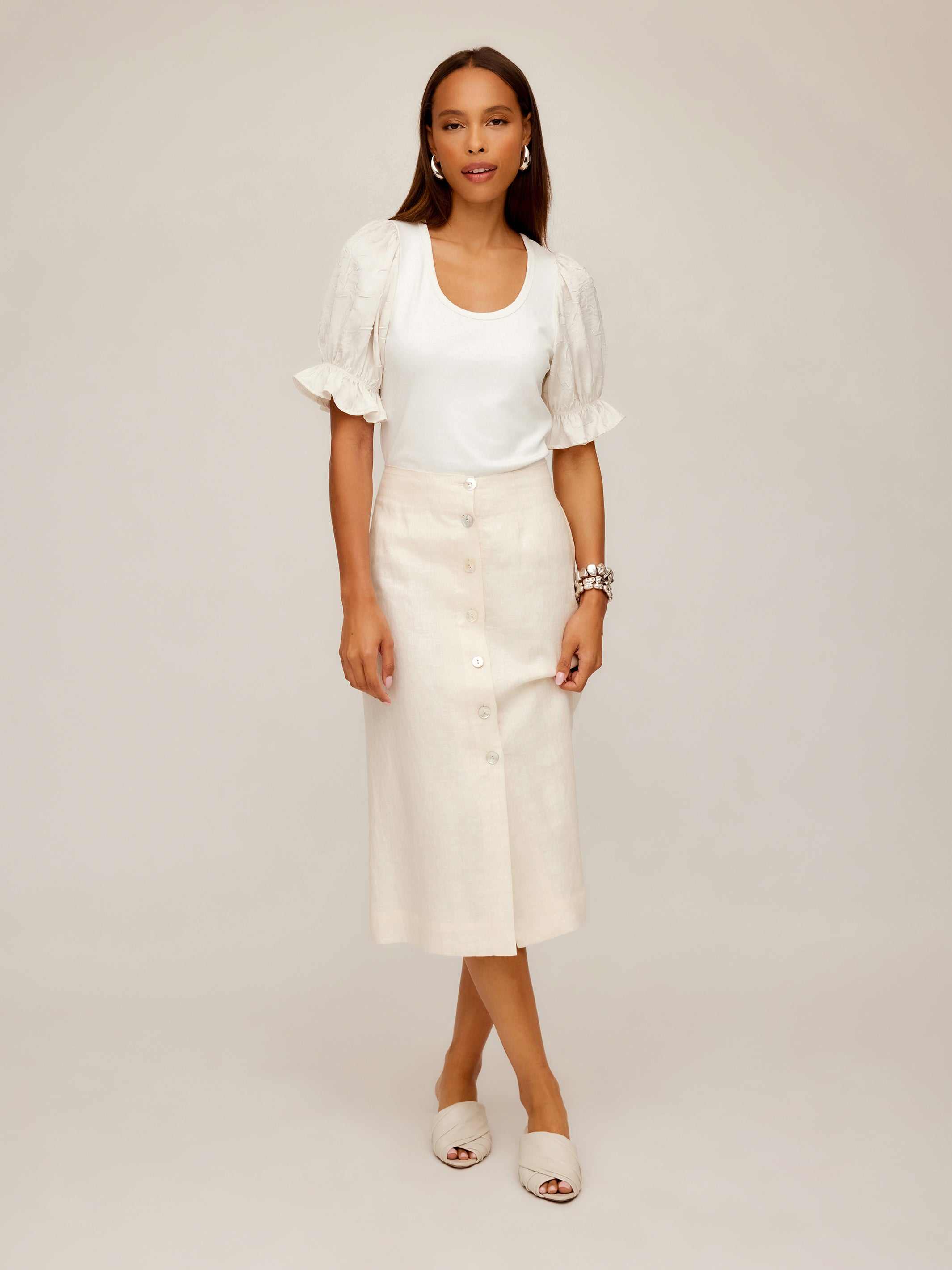 Woman wearing a beige Lori Midi Skirt with front buttons and a white puff-sleeve top