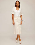 Woman wearing a beige Lori Midi Skirt with front buttons and a white puff-sleeve top