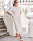 Woman wearing a cream Lori Midi Skirt with front shell buttons and a straight fit in a stylish outdoor setting