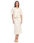 Woman wearing a cream Lori Midi Skirt with front shell buttons and a front slit made of 100% linen with straight fit and midi length