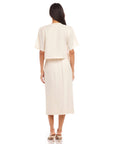 Back view of a woman wearing an off-white Lori Midi Skirt made of 100% linen with a straight fit and front slit.