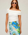 Woman wearing a white Lizzie One-Shoulder Top with rib knit fabric and side shirring detail paired with a colorful floral skirt