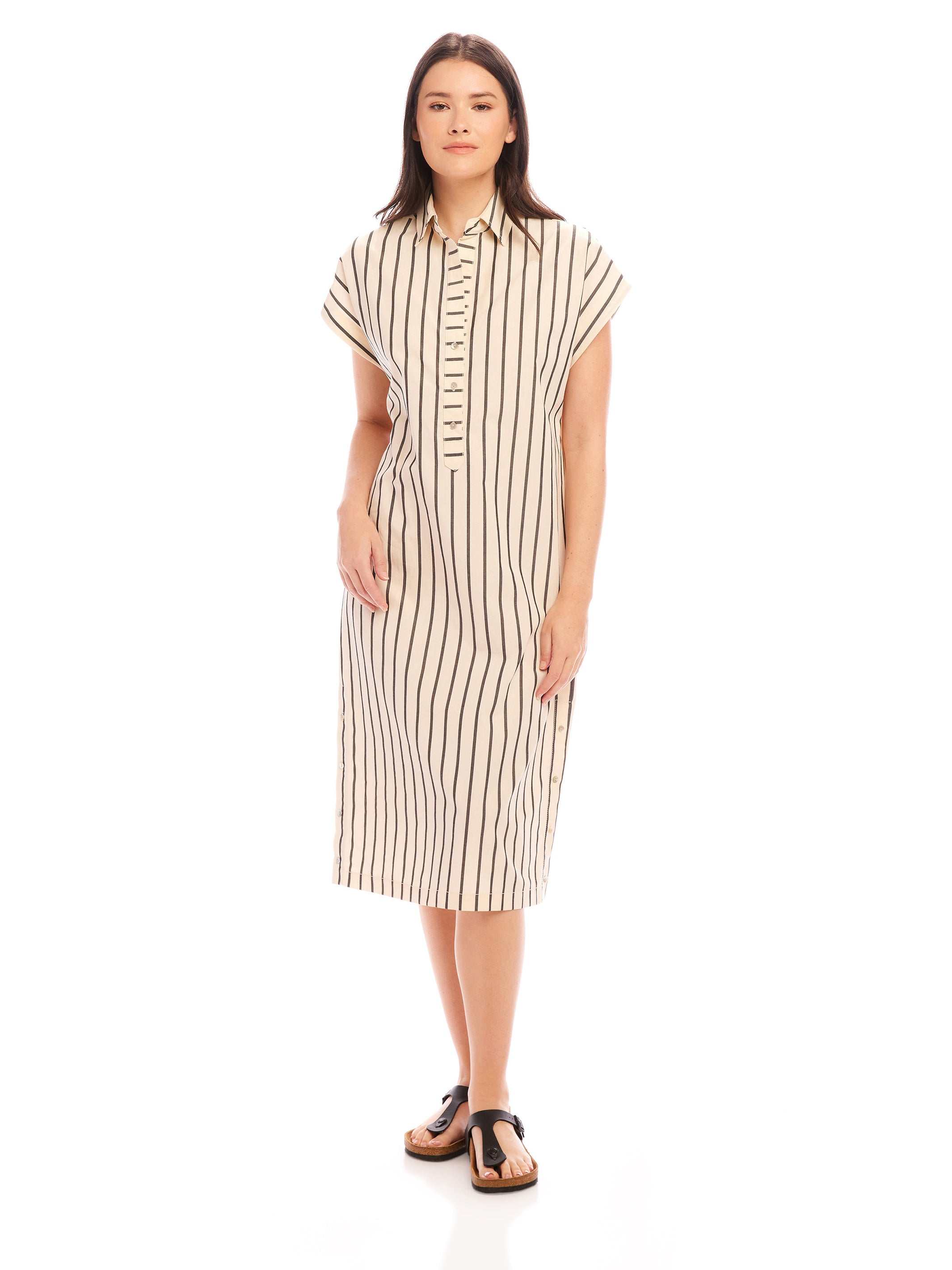 Woman wearing a Lucia Stripe Dress with vertical stripes, boxy fit, cap sleeves, collared neck, and side slit.