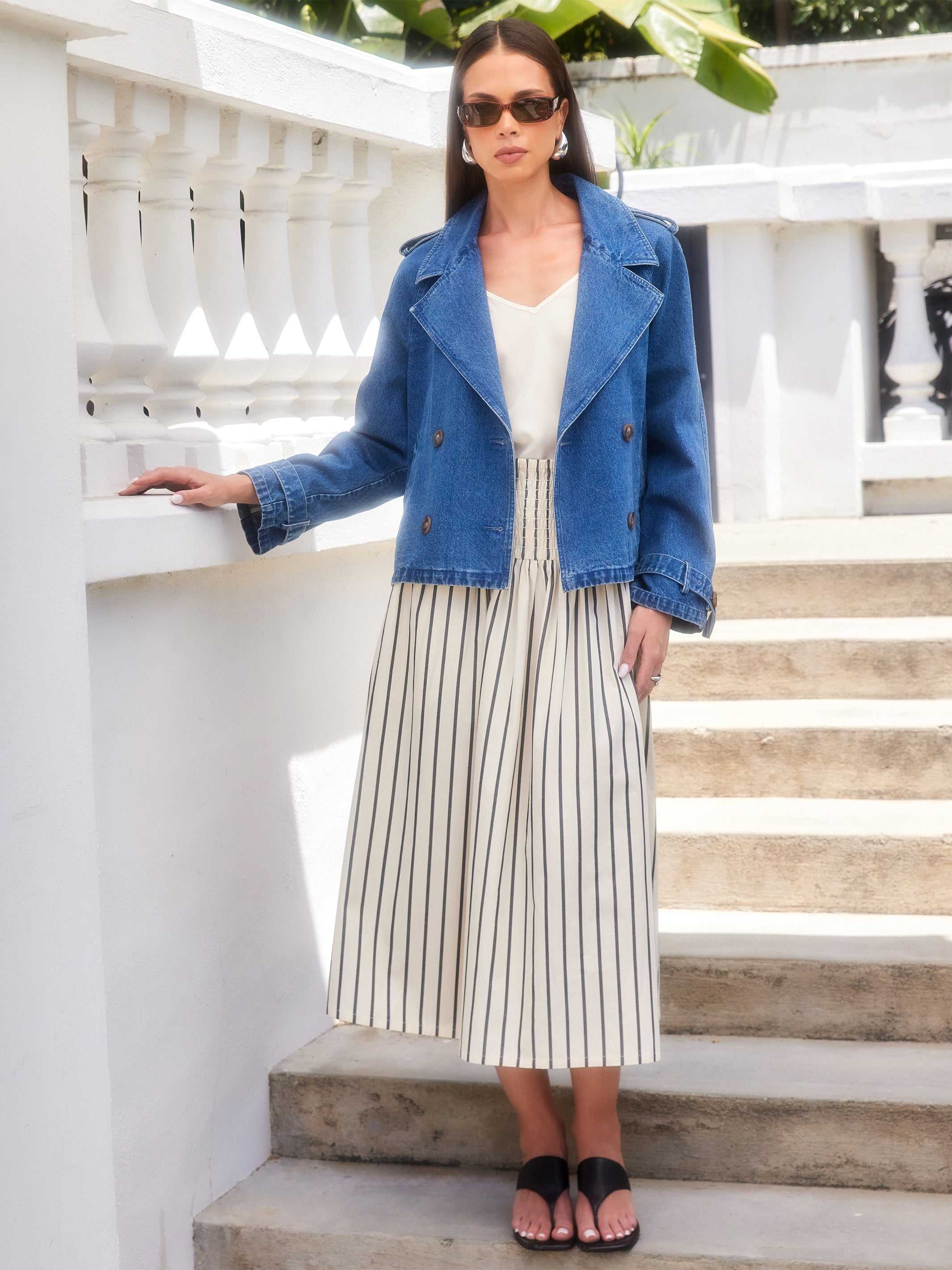 Woman wearing Rhea Stripe Skirt with vertical stripes, paired with white top and denim jacket outdoors on steps