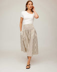 Woman wearing Rhea Stripe Skirt, a high-waisted midi cotton skirt with vertical stripes and elasticized sheered waist.