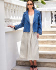 Woman wearing Rhea Stripe Skirt with vertical stripes, paired with white top and denim jacket outdoors on steps