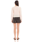 Back view of a woman wearing an Aubrey Button-Up Blouse with long bishop sleeves and pucker woven texture paired with black shorts
