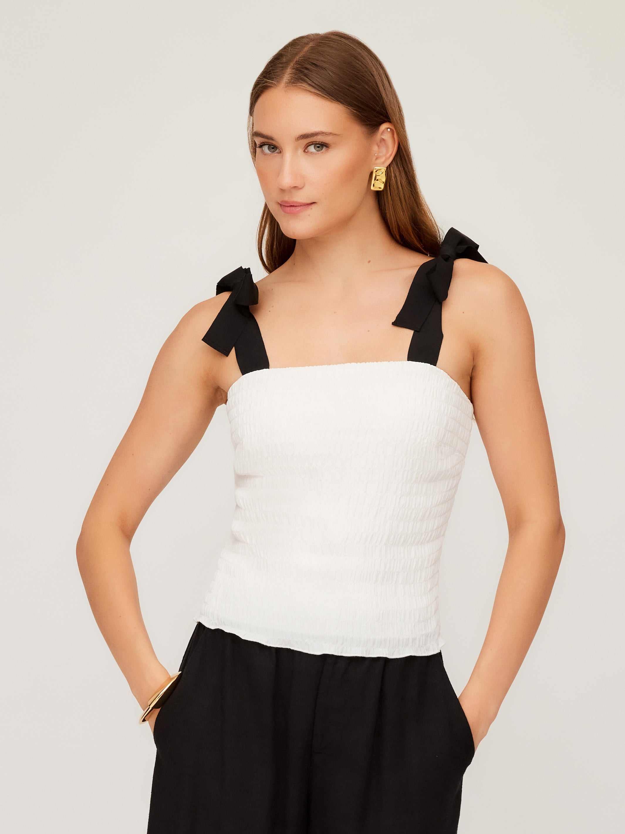 Woman wearing a white Annie Ribbon Tie Top with black adjustable tie straps and square neckline
