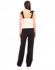 Back view of woman wearing Annie Ribbon Tie Top with black adjustable tie straps, square neck, paired with black wide-leg pants
