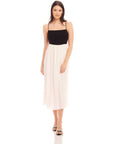 Woman wearing Anetta Contrast Midi Dress with black fitted top and white flowy skirt, adjustable spaghetti straps, and square neckline.