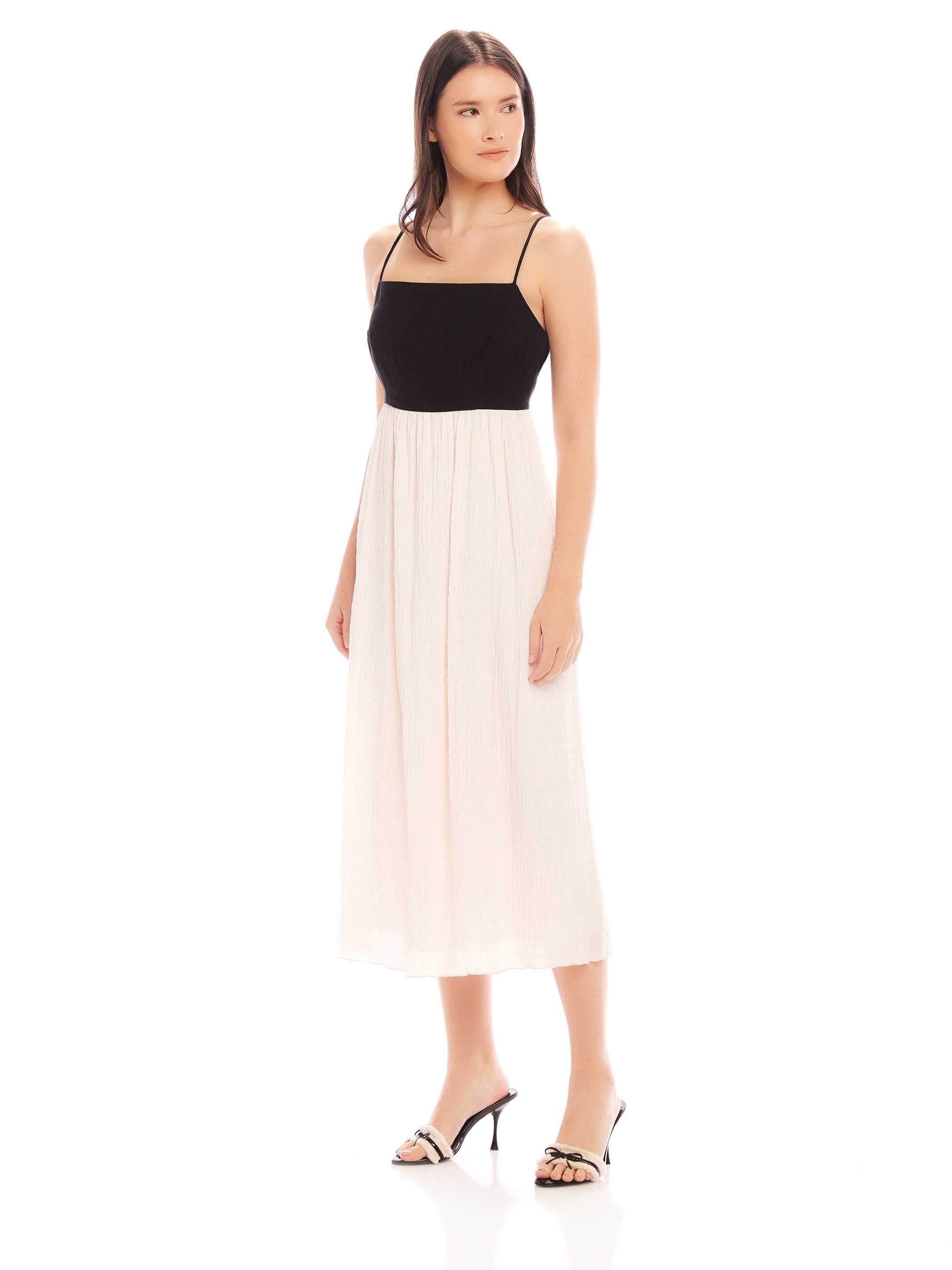 Woman wearing Anetta Contrast Midi Dress with fitted black top and flowy white skirt, spaghetti straps and square neckline.