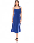 Woman wearing blue Serena Midi Dress with asymmetrical tie shoulder and scoop neck, midi length sheath style