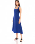 Woman wearing blue Serena Midi Dress with asymmetrical tie shoulder and scoop neck in a sheath silhouette