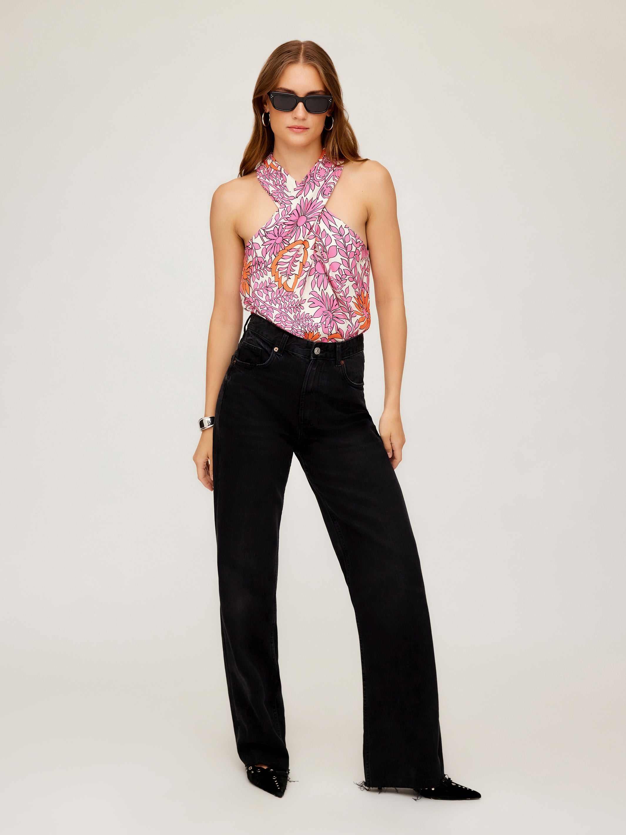 Woman wearing Sasha Halter Top with vibrant retro floral print and black pants.