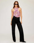 Woman wearing Sasha Halter Top with vibrant retro floral print and black pants.