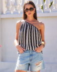 Woman wearing Louetta One-Shoulder Tank with black and white stripes and gold foil detail paired with ripped denim shorts outdoors