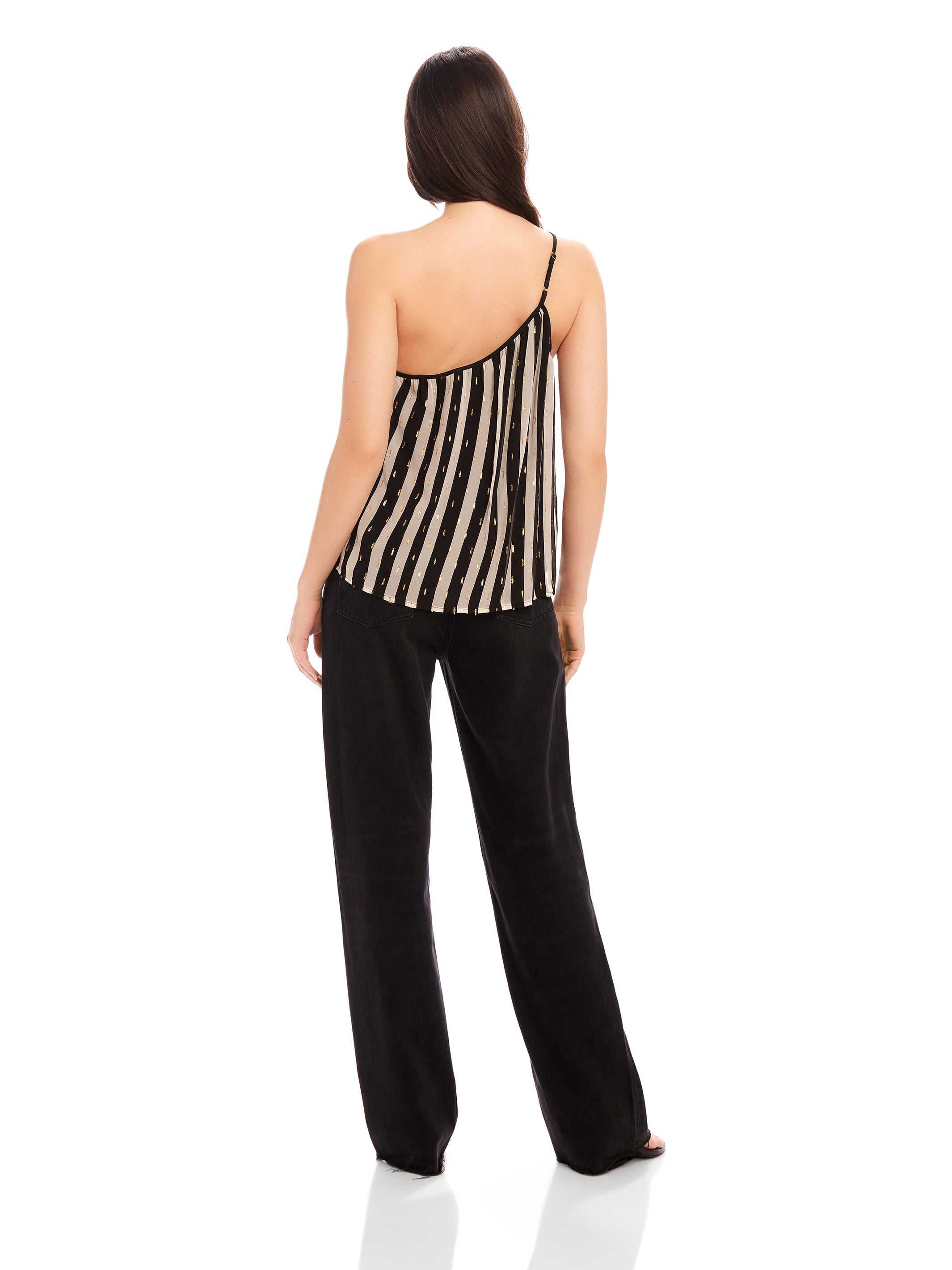 Back view of a woman wearing a Louetta One-Shoulder Tank with black and white stripes and metallic gold foil detail paired with black pants