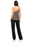 Back view of a woman wearing a Louetta One-Shoulder Tank with black and white stripes and metallic gold foil detail paired with black pants